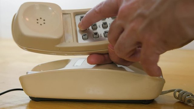 Making telephone call on vintage landline phone. Man dialing retro push button rotary dial telephone. 