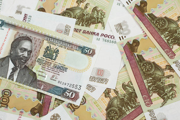 A close up image of a fifty Kenyan shilling bank note in macro with Russian one hundred ruble bills
