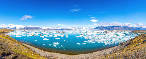 Panoramic pictures over Joekularson glacier lagoon with frifting iceberg in summer