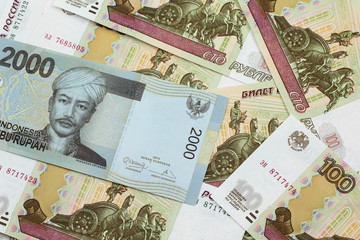 A grey, two thousand Indonesian rupiah bank note with Russian one hundred ruble bills close up in macro