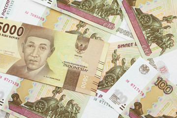An orange, five thousand Indonesian rupiah bank note with Russian one hundred ruble bills close up in macro