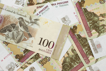 A Venezuelan one hundred Bolivares bank note, close up in macro on a bed of Russian one hundred ruble bank notes