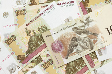 A Venezuelan one hundred Bolivares bank note, close up in macro on a bed of Russian one hundred ruble bank notes