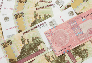 A close up image of a red, ten taka bank note from Bangladesh on a bed of Russian one hundred ruble bank notes in macro