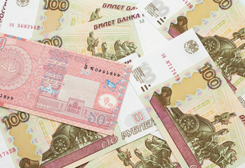 A close up image of a red, ten taka bank note from Bangladesh on a bed of Russian one hundred ruble bank notes in macro