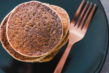 close-up of vegan banana pancakes stack on black plate with copper fork