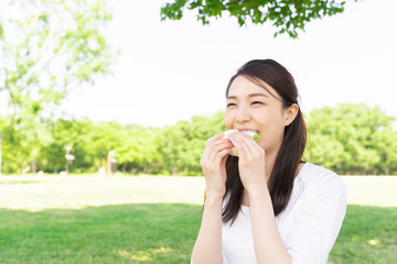 サンドイッチを食べる女性　屋外