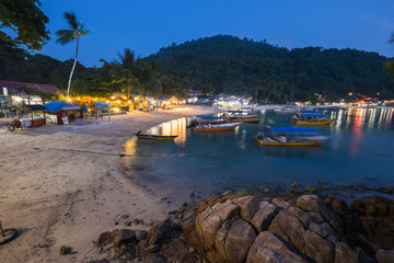 Fototapeta na wymiar Pulau Perhentian, Terengganu - August 14th, 2018 : Beautiful view of small Perhentian Island with multiple boats during blue hour. Image contains noise and soft focus
