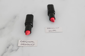 beauty industry competition, two identhical looking lipsticks with Original Product and Product Dupe labels