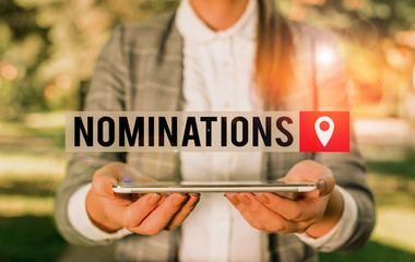 Writing note showing Nominations. Business concept for the act of officially suggesting someone for a job or position Outdoor scene with business woman holds lap top with touch screen