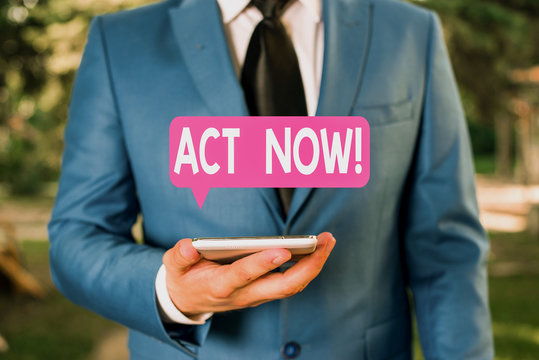 Text sign showing Act Now. Business photo text do not hesitate and start working or doing stuff right away Businessman in blue suite stands with mobile phone in hands