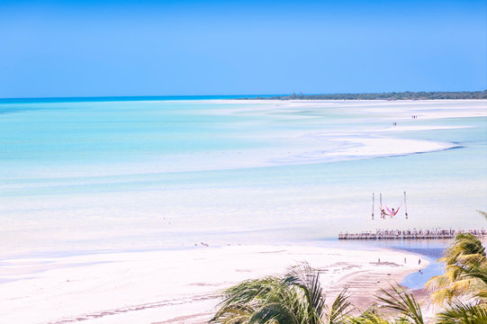 Tourists walk at low tide of the Caribbean Sea on the island of Holbox Mexico. Incredible panoramic view of the white sandy beaches of the Caribbean Sea