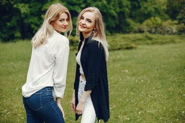 Fototapeta premium Pretty girls in a summer park. Friends walking in a city. Ladies with blonde hair