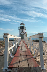 Fototapeta na wymiar Brand Point Lighthouse with its long footbridge , located on Nantucket Island in Massachusetts, decorated for the holidays with a Christmas wreath and crossed oars.