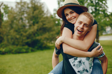 Lovely couple in a summer park. Boy with his girlfriend. Girl in a brown hat.