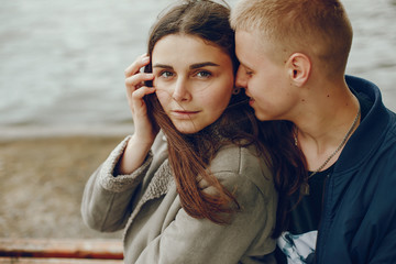 Lovely couple in a summer park. Boy with his girlfriend. Couple sitting near water