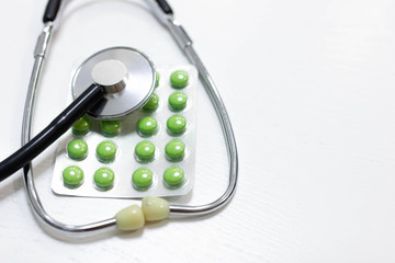 stethoscope and green pills, medical treatment and pharmaceuticals concept.