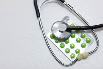stethoscope and green pills, medical treatment and pharmaceuticals concept.