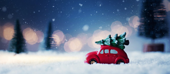 Driving home for christmas - red car with christmas tree in a romantic winter scene...  - 309079132