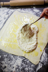 Baking domestic rolls with cheese. Putting cheese on dough for rolls