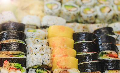 Fresh sushi rolls with salmon, avocado, tuna and cucumber. Maki plate with rice and nori. Delicious Japanese food with sushi roll in close up picture. Healthy kale and sushis. Holiday food setting.