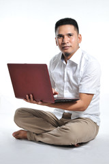 Young Asian business man or Young Asian entrepreneur sit on the white floor holding laptop. Excited of young Asian freelancer.