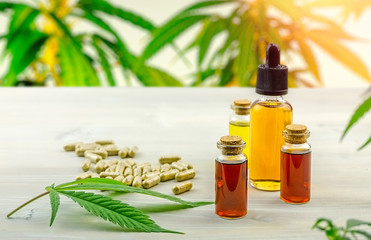Full Spectrum Cannabis CBD and THC oils and pills on wooden table