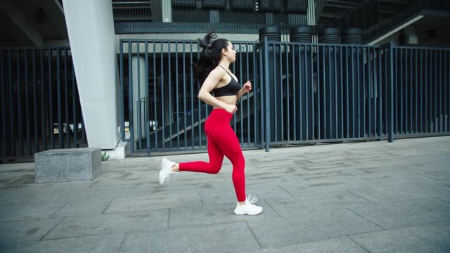 Female runner training outdoor in slow motion. Fitness woman running on street