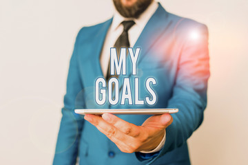 Conceptual hand writing showing My Goals. Concept meaning a future or desired result that a demonstrating commits to achieve Businessman in blue suite with a tie holds lap top in hands