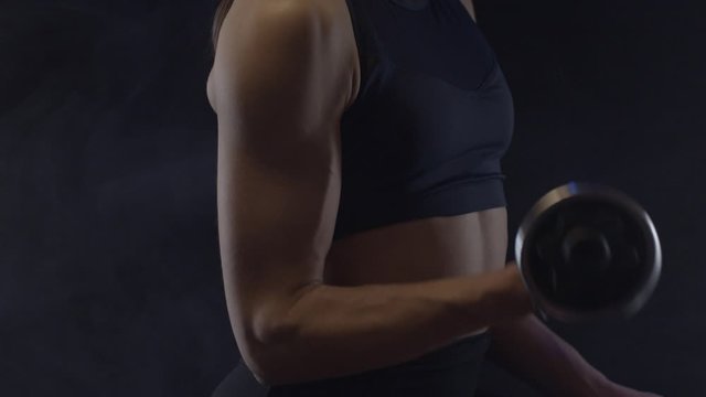 Fit woman doing biceps curls with dumbbells, close up, shot in slow motion