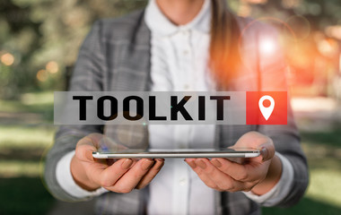 Writing note showing Toolkit. Business concept for set of tools kept in a bag or box and used for a particular purpose Outdoor scene with business woman holds lap top with touch screen