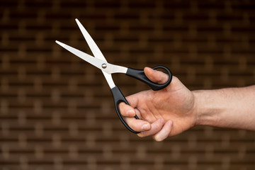 Scissors on Brick Background. Hand Holding Scissors.
