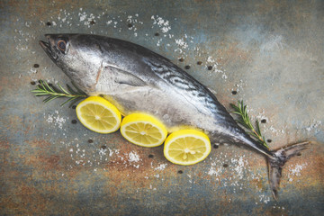 Fresh fish with herbs spices rosemary and lemon - Raw fish seafood on black plate background top view , Longtail tuna , Eastern little tuna fish