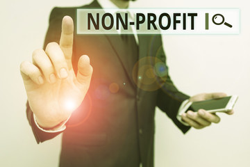 Writing note showing Non Profit. Business concept for not making or conducted primarily to make profit organization Male human wear formal work suit hold smartphone using hand