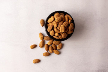 natural and organic almonds in a black bowl, top view.