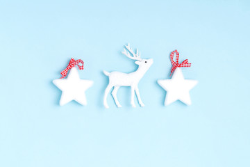 New Year and Christmas composition from white stars, deer on pastel blue background. Top view, flat lay, copy space