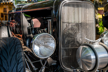 Black shiny vintage retro car with round headlights and a large grille exhibited at a provincial town street exhibition