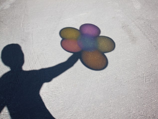 shadow of a person holding a handful of balloons on a sunny day