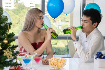 Young couple celebrating new year together, drinking beer together.