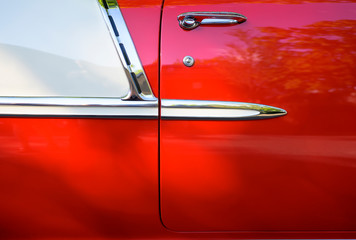 Side of a bright red vintage retro convertible car with chrome details and moldingsю