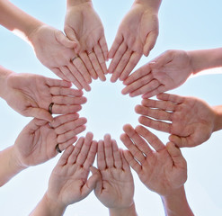 overhead view of a group of people making a circle shape with their hands directly below the sun with a lens flare toned with a retro vintage instagram filter
