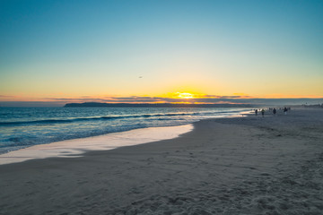 Obraz premium Sunset on the beach with silhouette of people on seashore