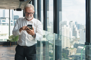 portrait of caucasian senior business executive using smartphone in office