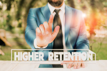 Writing note showing Higher Retention. Business concept for ability of an organization to retain its employees Businessman with pointing finger in front of him