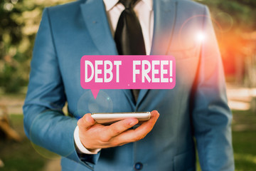 Text sign showing Debt Free. Business photo text does not owning any money or things to any individual or companies Businessman in blue suite stands with mobile phone in hands