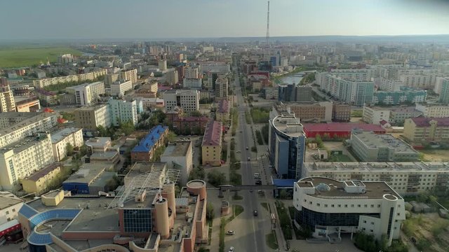 Yakutsk cityscape skyline city ​​center main street capital of Sakha Republic. Far East Russia. City permafrost. Soviet buildings roofs. Road traffic cars ride Summer sunny day horizon. Aerial forward