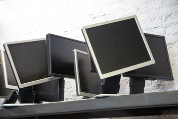 Photo of several computer monitors sitting on metal shelf ready to be turned on