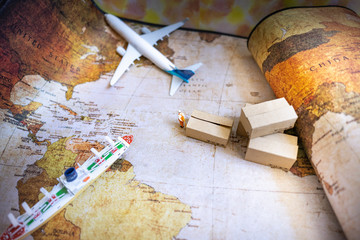 Miniature people: Worker and brown paper box on world map with airplane, ship using as background...