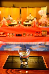 雛飾りを背景にグラスの水です