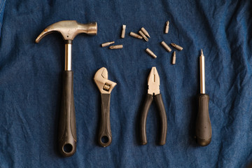 Hand tools such as hammers, pliers, wrench and screwdrivers are arranged on a blue denim background.